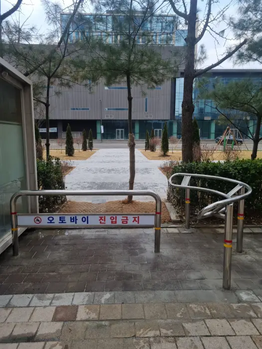 신축 단지 광장 보행로에 혼합 배치된 직선형과 곡선형 볼라드